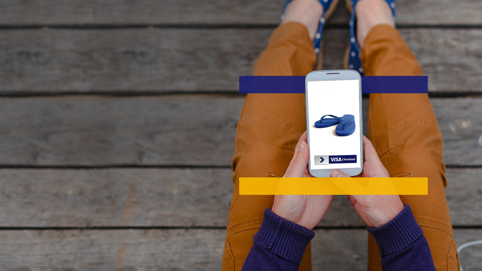 Person looking at a phone in their lap that displays a pair of sandals and the purchasing service Visa Checkout. 