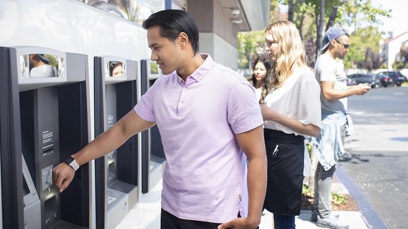 Man using smartwatch during Contactless transaction at outdoor ATM.