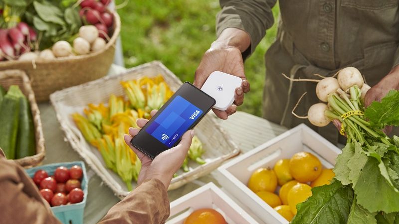 Woman tapping to pay at farmers market with mobile phone 