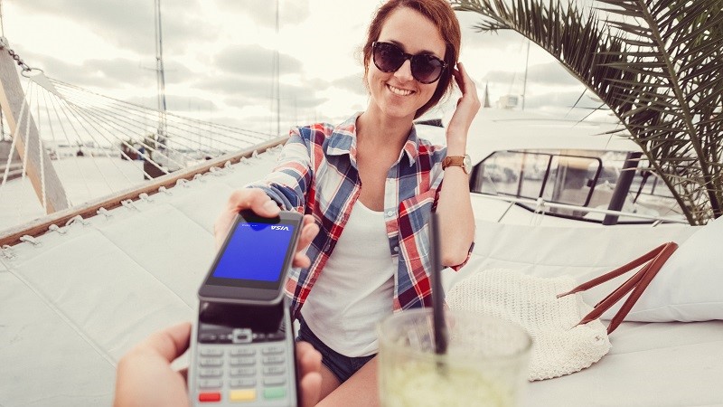 Woman paying with the phone while on vacation