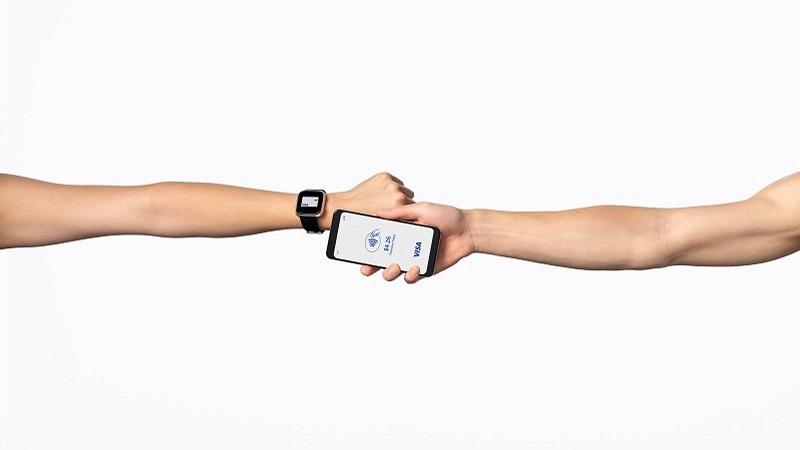 Consumer who is preparing to tap to pay using a smartwatch against a mobile phone.