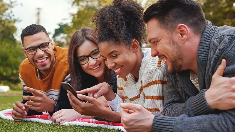 group of people lying down in park looking at mobile